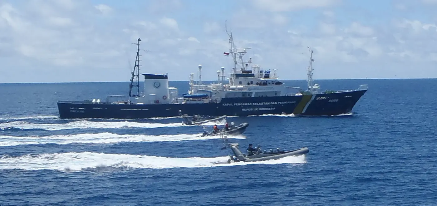 Kapal patroli besar menghentikan perahu nelayan kecil di perairan laut terbuka